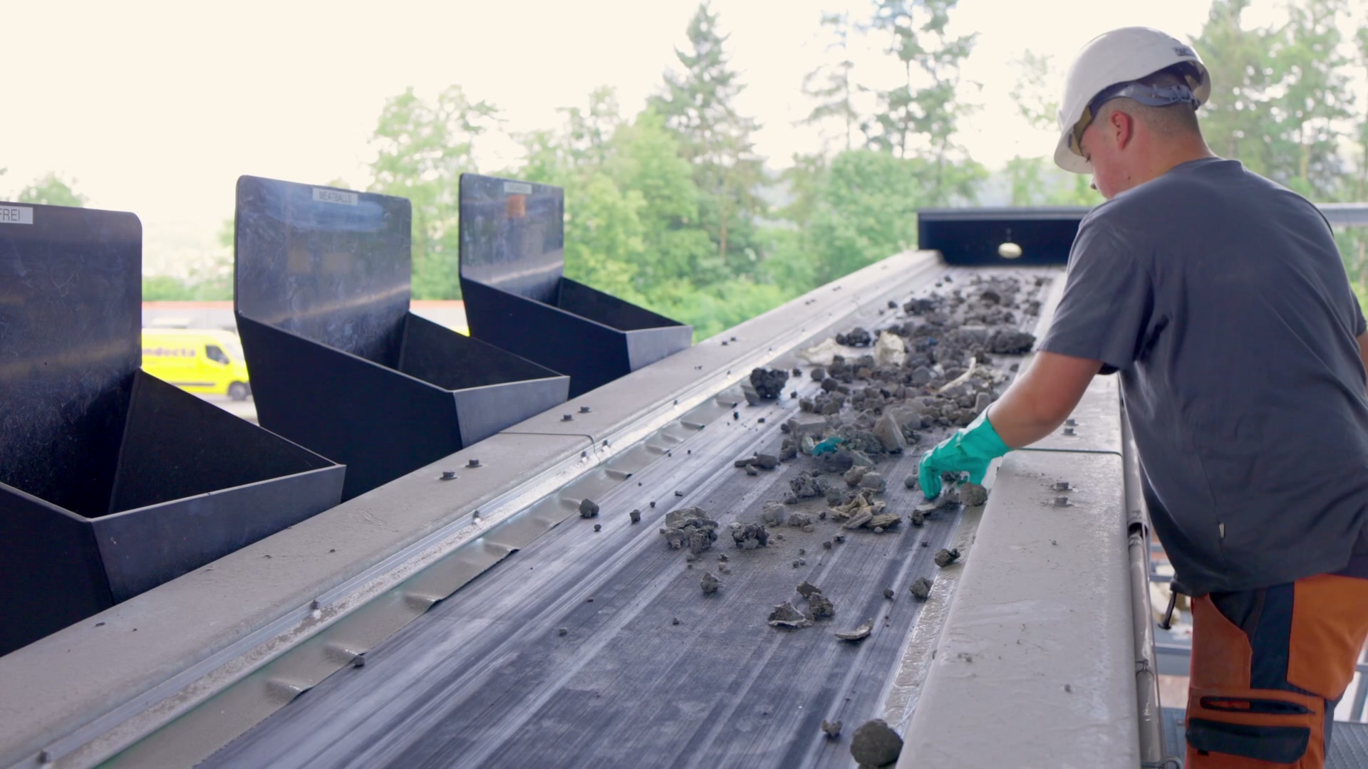 Bottom ash on the sorting conveyor at Centro Uno, with operator inspecting recovered fragments.